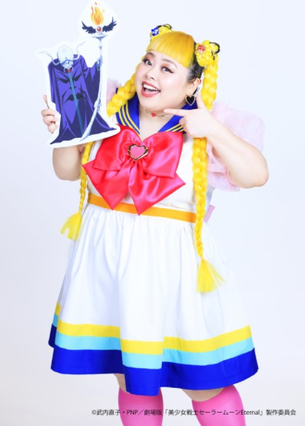 Naomi Watanabe vestida como Sailor Moon apontando para uma gravura da Zirconia
