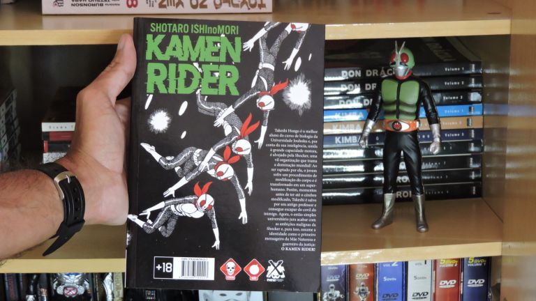 Imagem: Capa traseira do mangá e boneco do Kamen Rider.