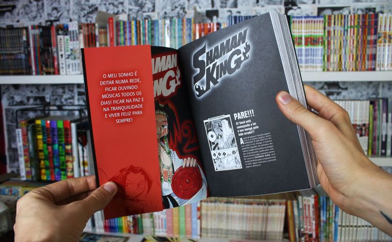 Imagem: mangá aberto, com a última página à direita e a orelha da sobrecapa à esquerda no volume 1 de Shaman King