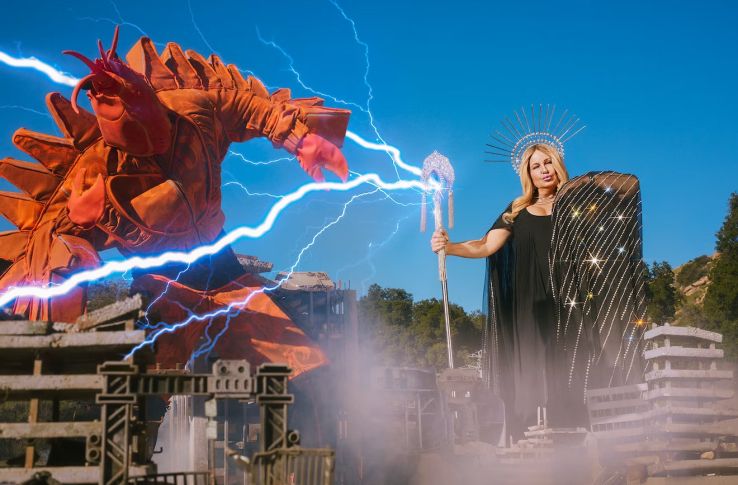 imagem: Jennifer em uma roupa inspirada na estátua da liberdade ataca um monstro lagosta com um cetro que dispara raios