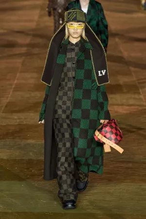 imagem: modelo com casaco xadrez preto e verde escuro e bolsa xadrez preto e vermelho.